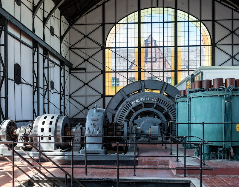 Industrial generator and machinery in a vintage power station with large arched windows