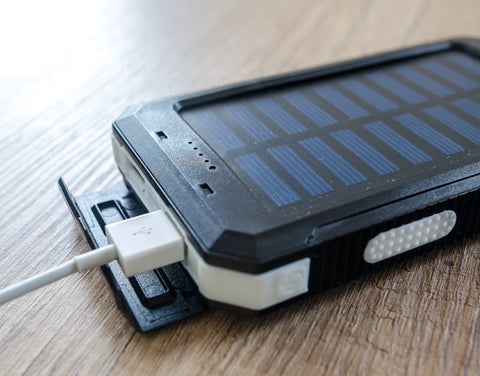Close-up of a solar power bank charging with USB cable on a wooden surface
