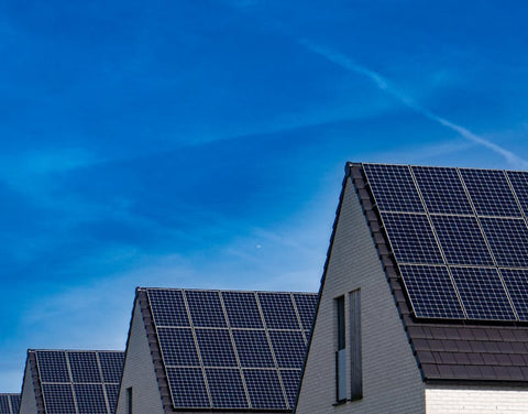 Modern houses with solar panels on rooftops under clear blue sky