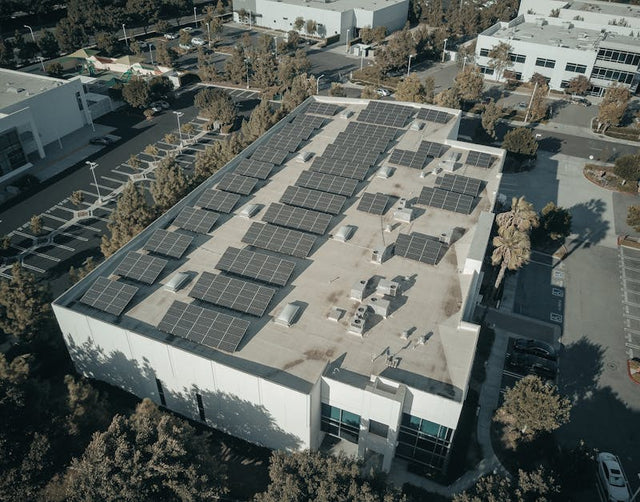 Aerial view of a commercial building with rooftop solar panels in a business park