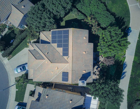 Aerial view of house with rooftop solar panels in suburban neighborhood