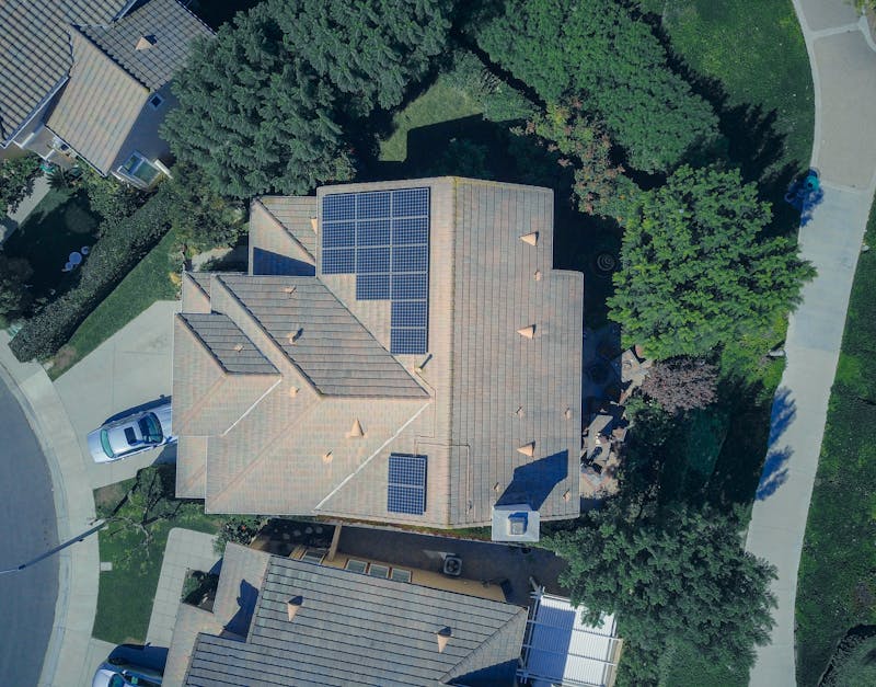 Aerial view of a house with solar panels on the roof in a suburban neighborhood