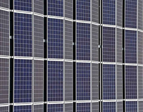 Close-up of multiple blue photovoltaic solar panels in a clean, grid-like arrangement