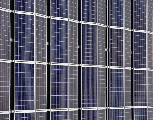 Close-up of multiple blue photovoltaic solar panels in a clean, grid-like arrangement